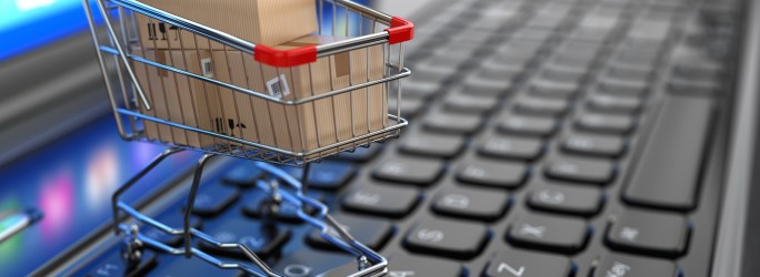 E-commerce. Shopping cart with cardboard boxes on laptop. 3d