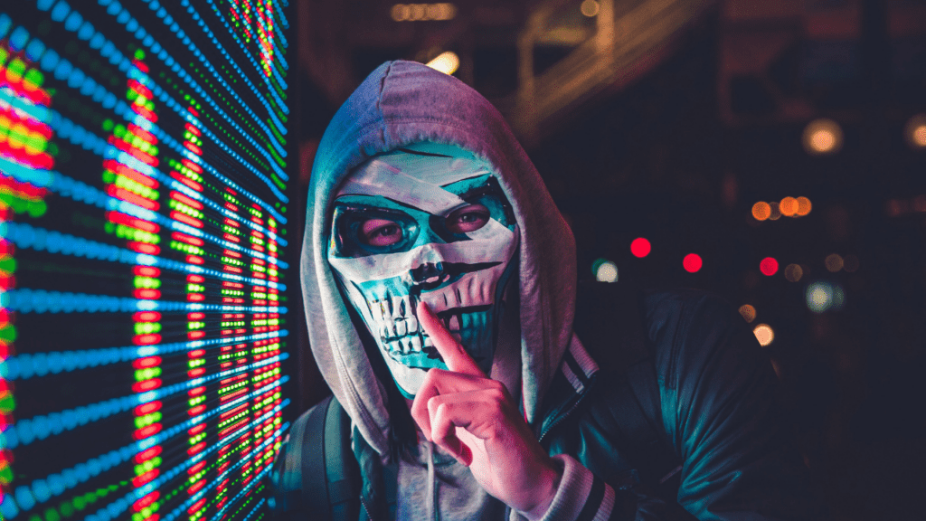 Hacker mascarado pedindo silêncio (Imagem: Max Bender/Unsplash)