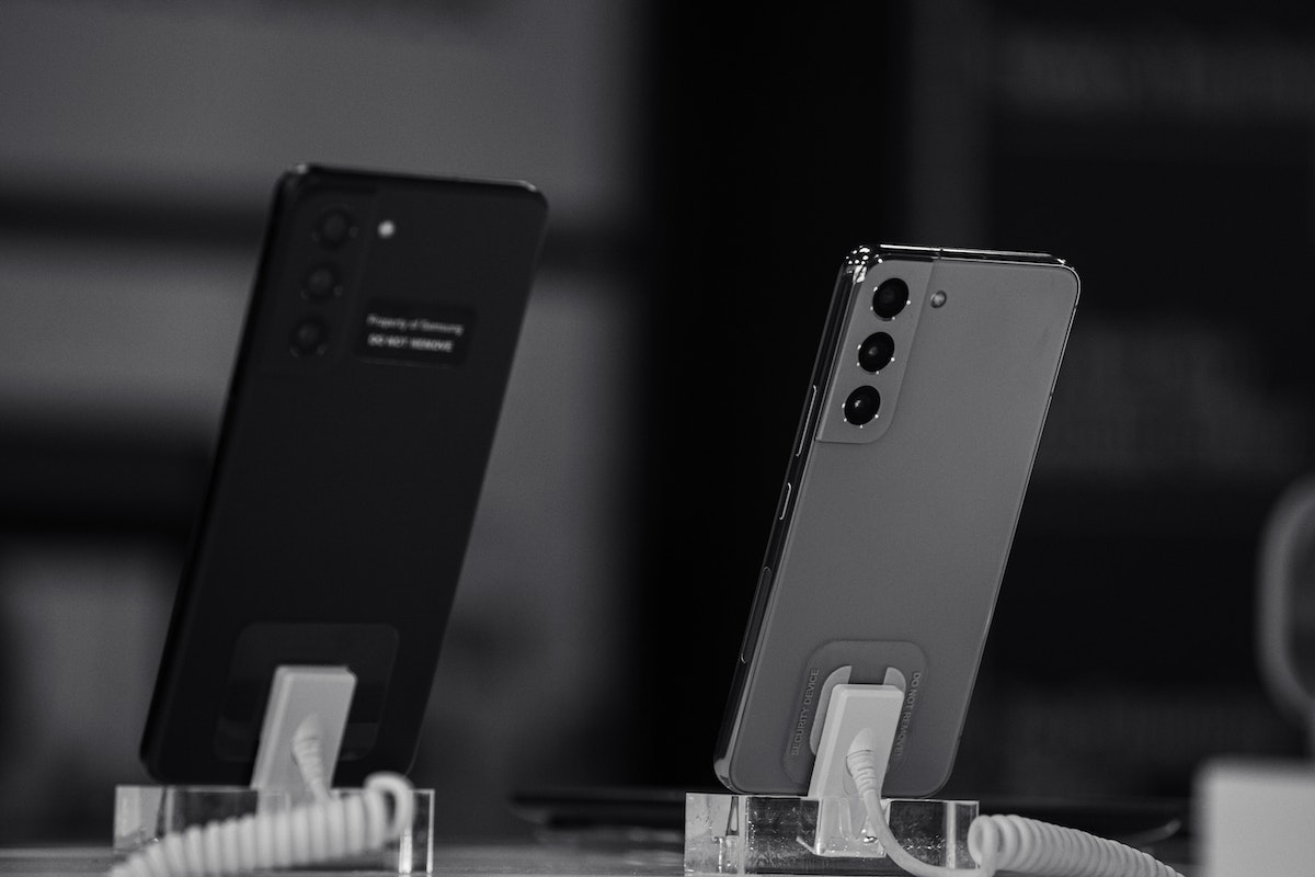 Dois celulares em um apoio. Um é preto e o outro é cinza