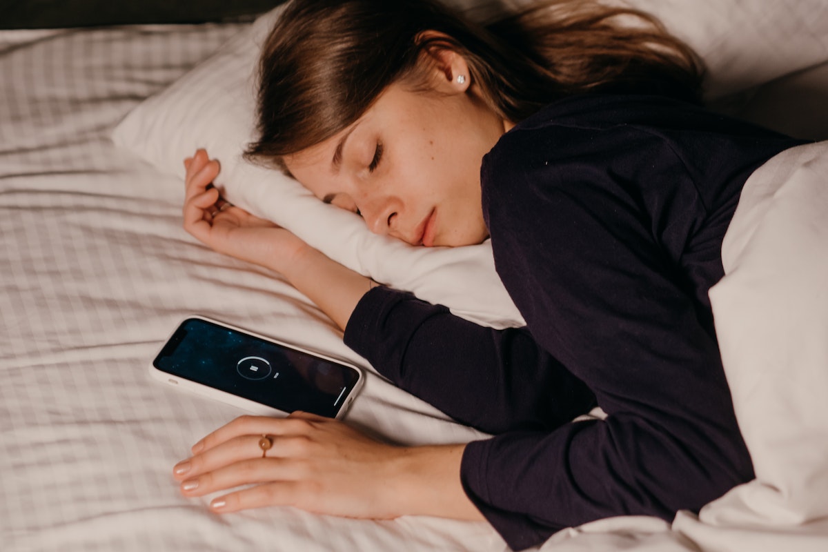 Mulher dormindo com o celular na cama
