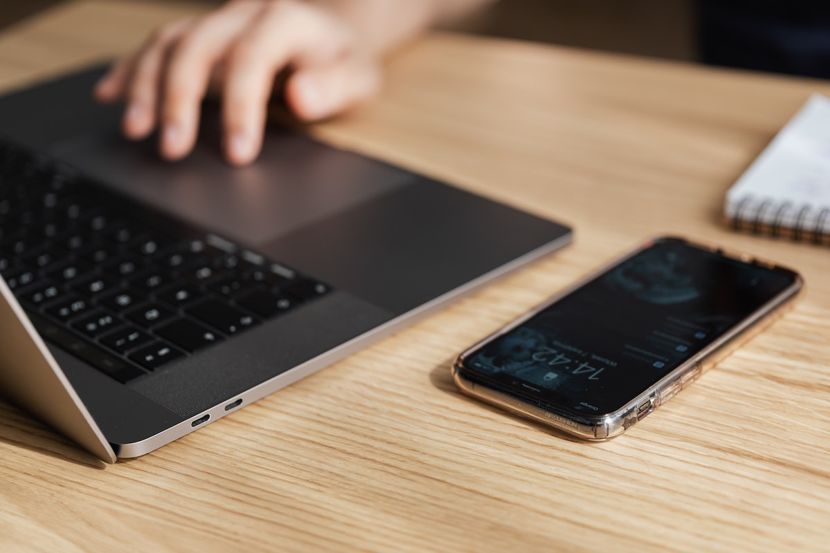 A imagem de um celular e um notebook em cima de uma mesa de madeira