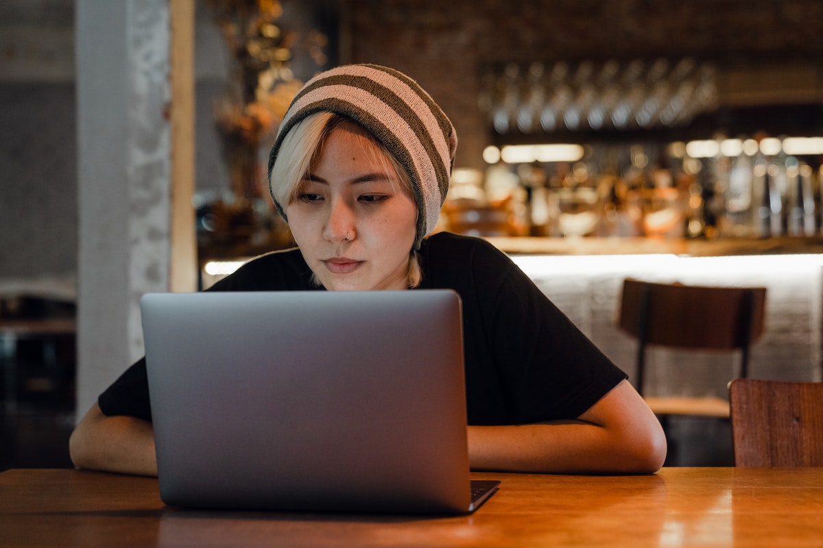 Uma mulher sentada em uma mesa, utilizando o seu notebook