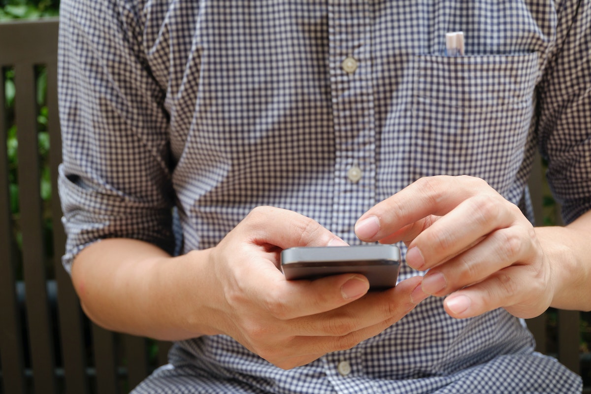 Homem segurando o seu celular na mão 