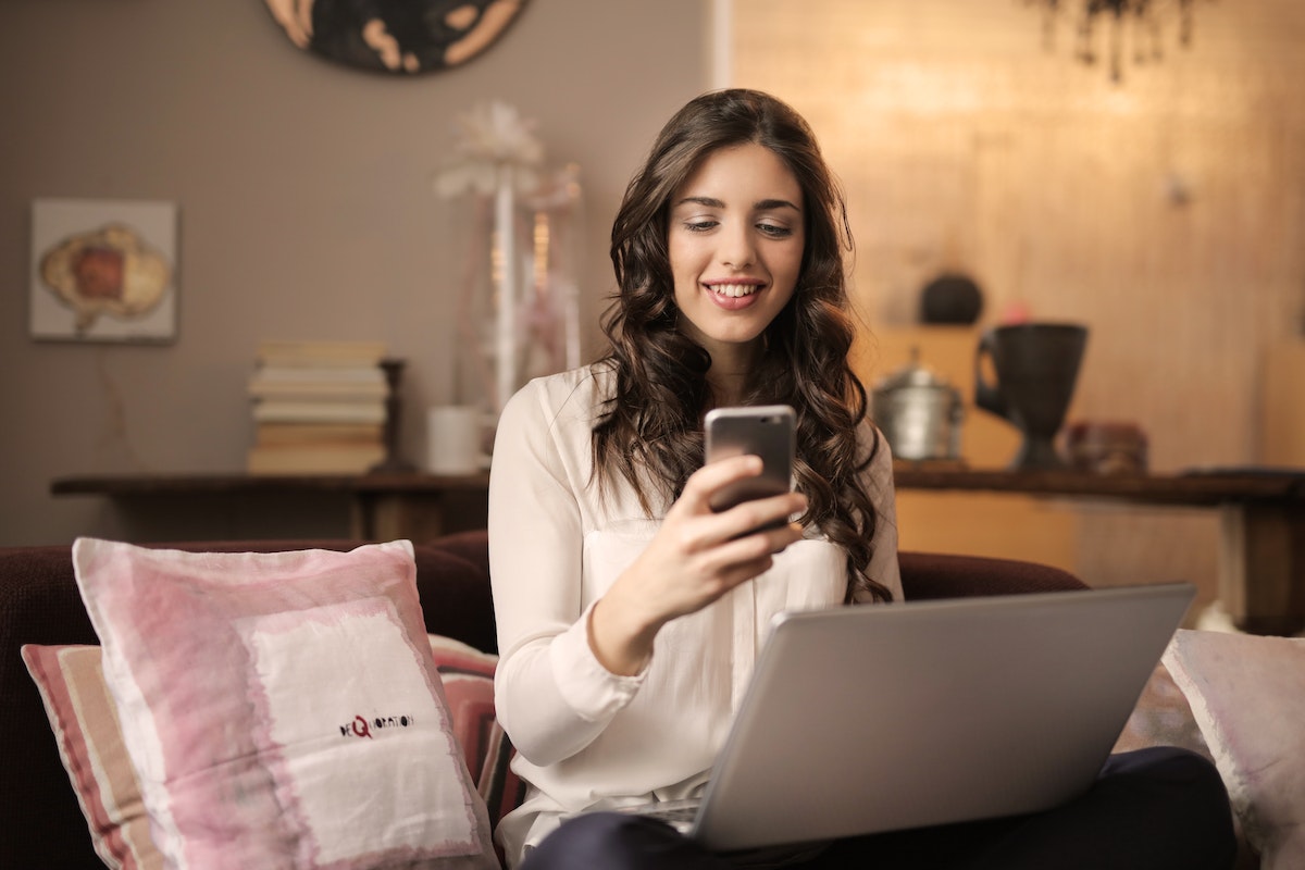 Mulher com seu smartphone sentada na sala de casa, conferindo app para aumentar score