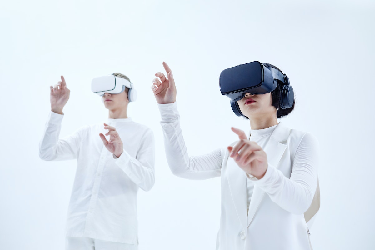 Duas pessoas testando um óculos de realidade virtual em um ambiente totalmente branco 
