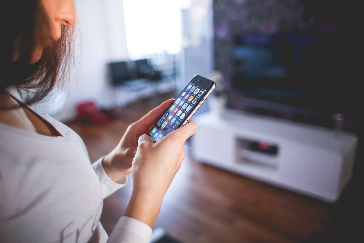 Uma mulher mexendo em seu smartphone controlando sua casa inteligente