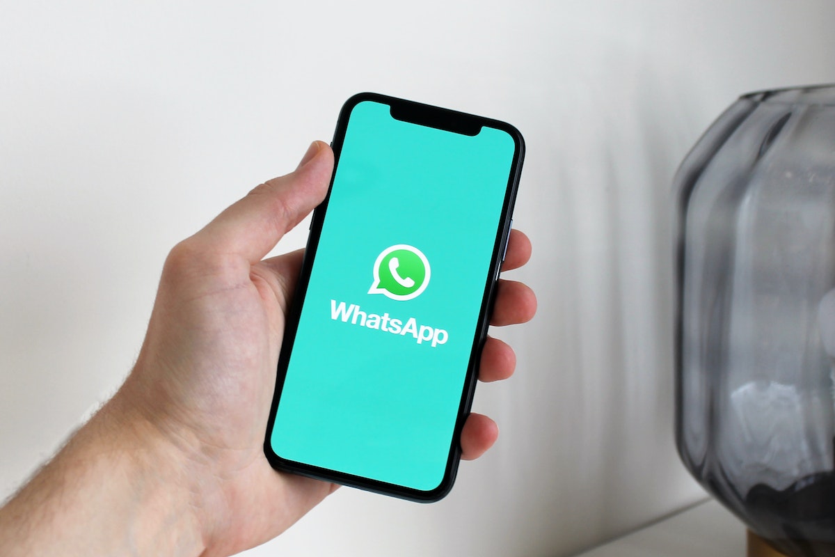 Pessoa segurando o smartphone na mão com a tela de abertura do WhatsApp