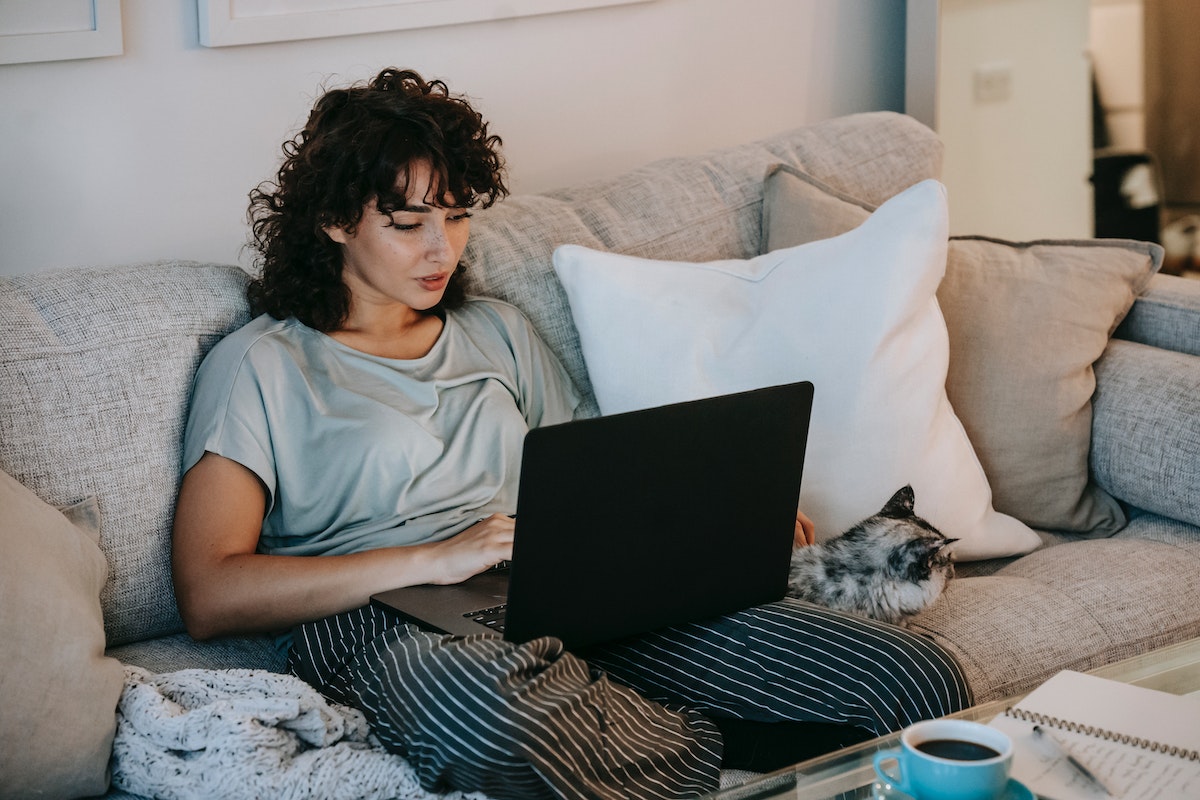 Uma mulher sentada no sofá com o notebook no colo, tentando assistir filmes online grátis no pc