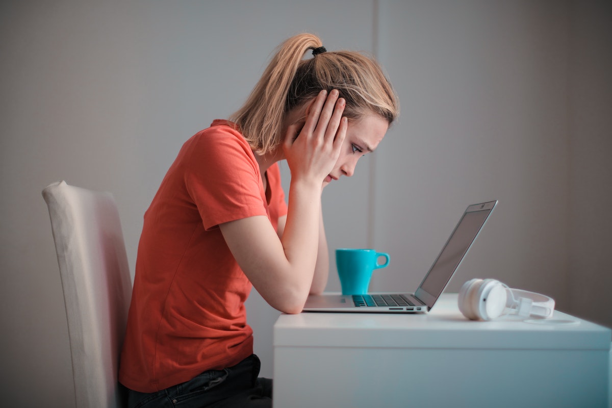 Mulher aparentemente preocupada enquanto olha para seu notebook que está na mesa