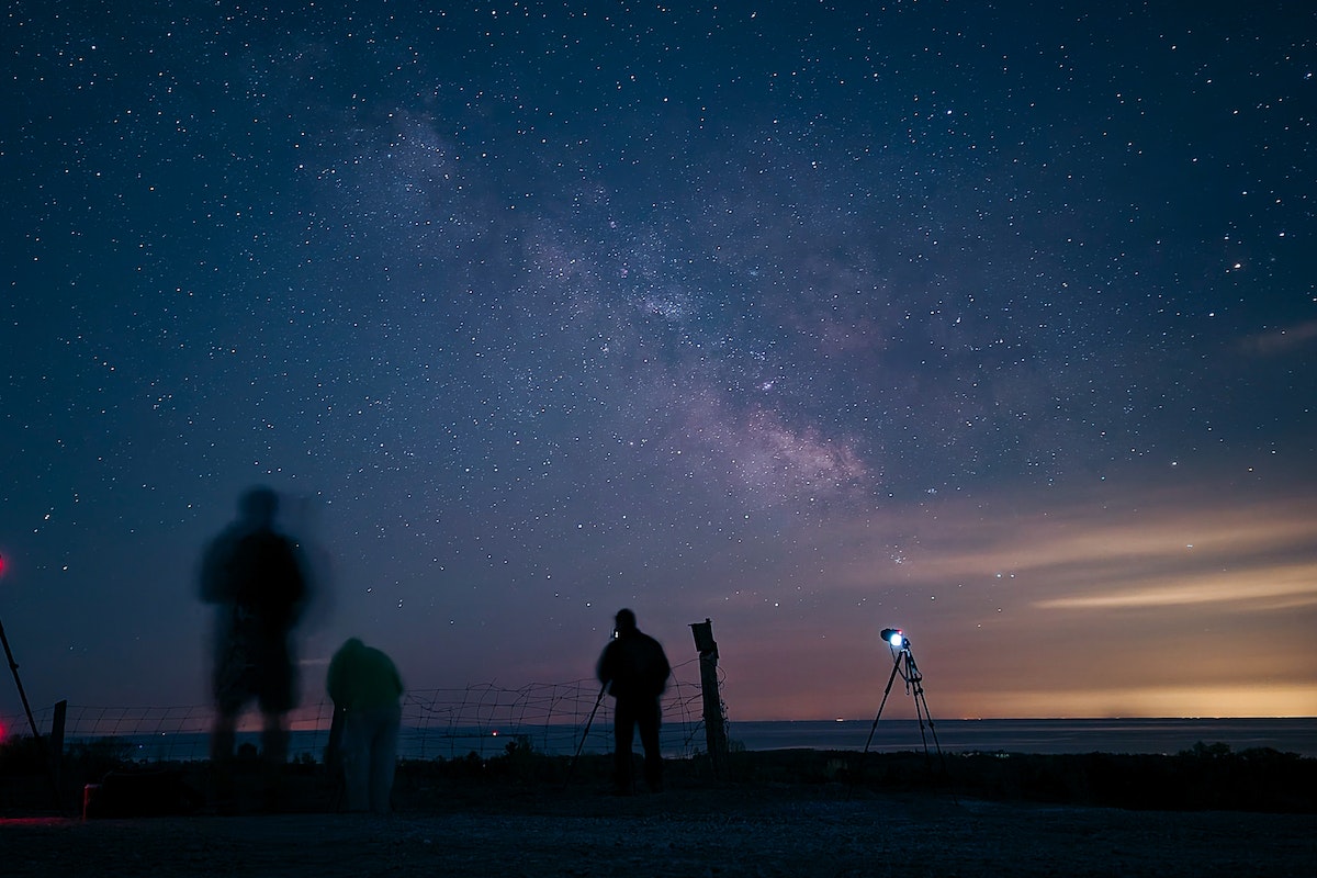 Pessoas tirando foto do céu que está totalmente estrelado 