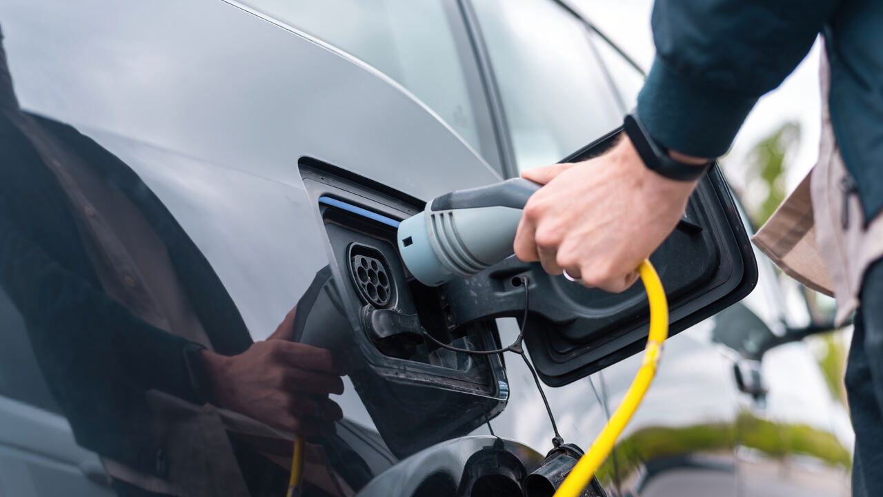 Homem recarregando carros elétricos fabricados pela Huawei e Xiaomi