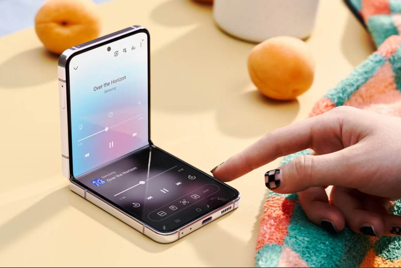 Celular Samsung Galaxy Z Flip 2024 apoiado em uma mesa, enquanto alguém toca em sua tela