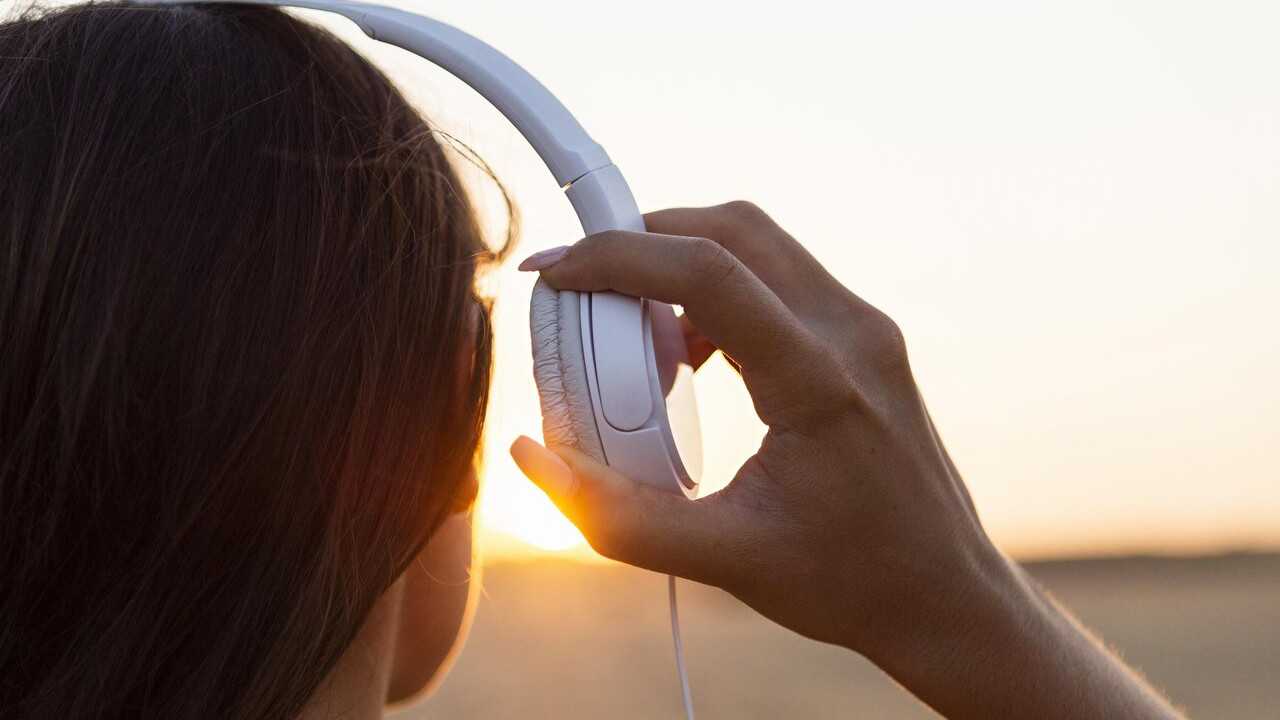 Mulher escutando música ao pôr do sol com fones de ouvido em 2024