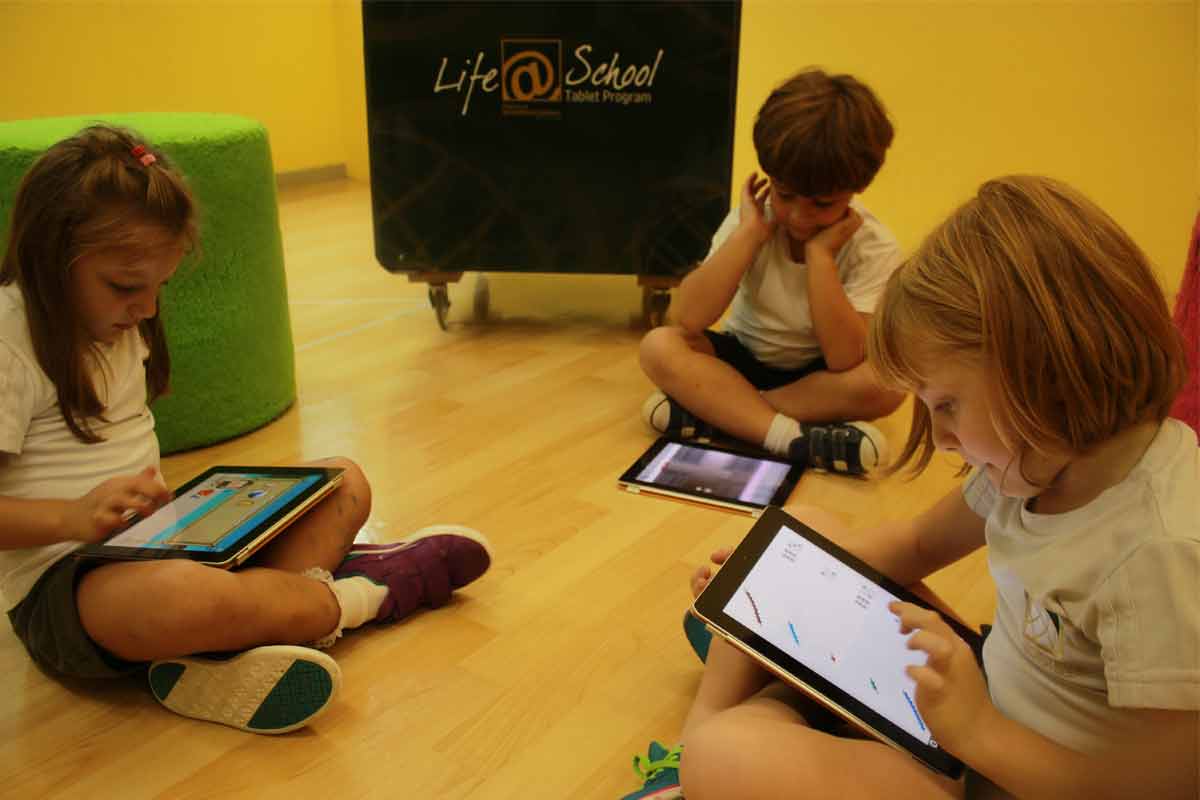 crianças sentadas no chão mexendo em um tablet