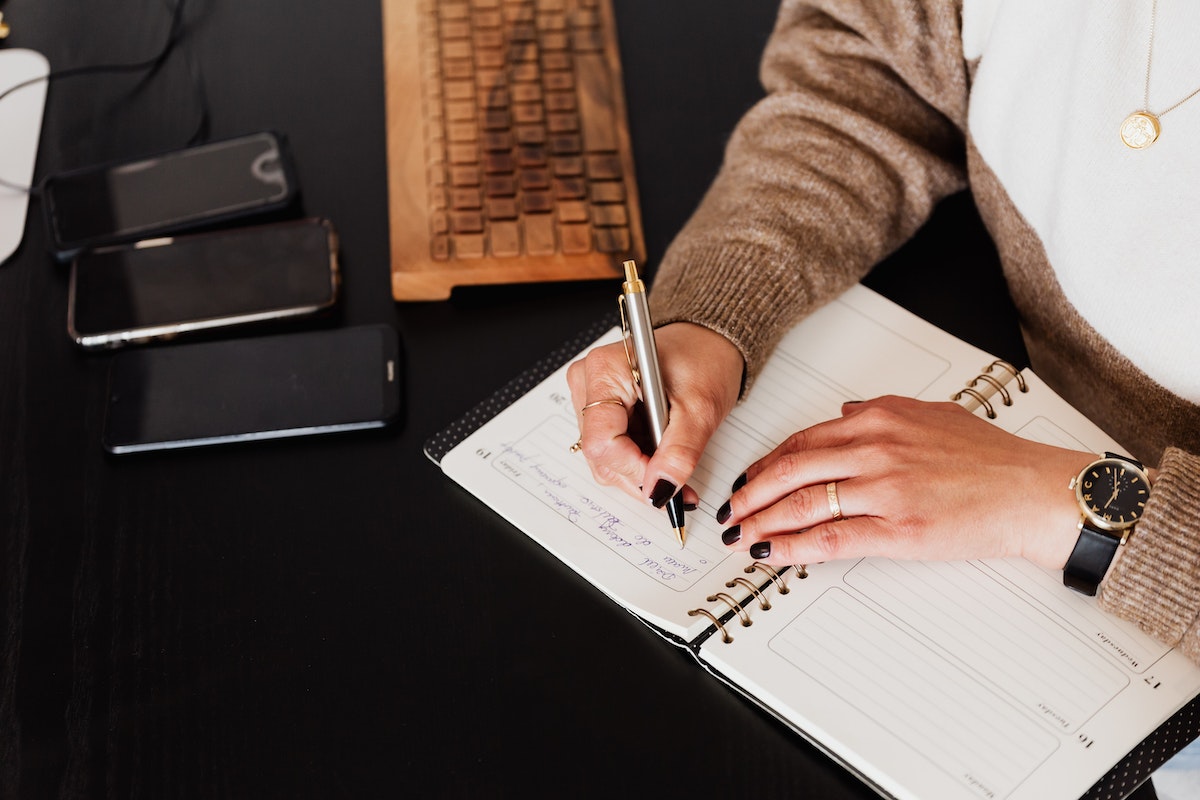 Uma pessoa faz anotação em um caderno enquanto analisa a melhor forma de comprar um celular novo