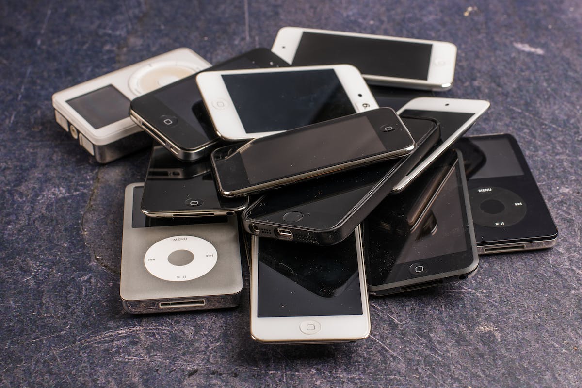 Uma pilha de celulares que estão quebrados. Entre eles, há muitos aparelhos da apple