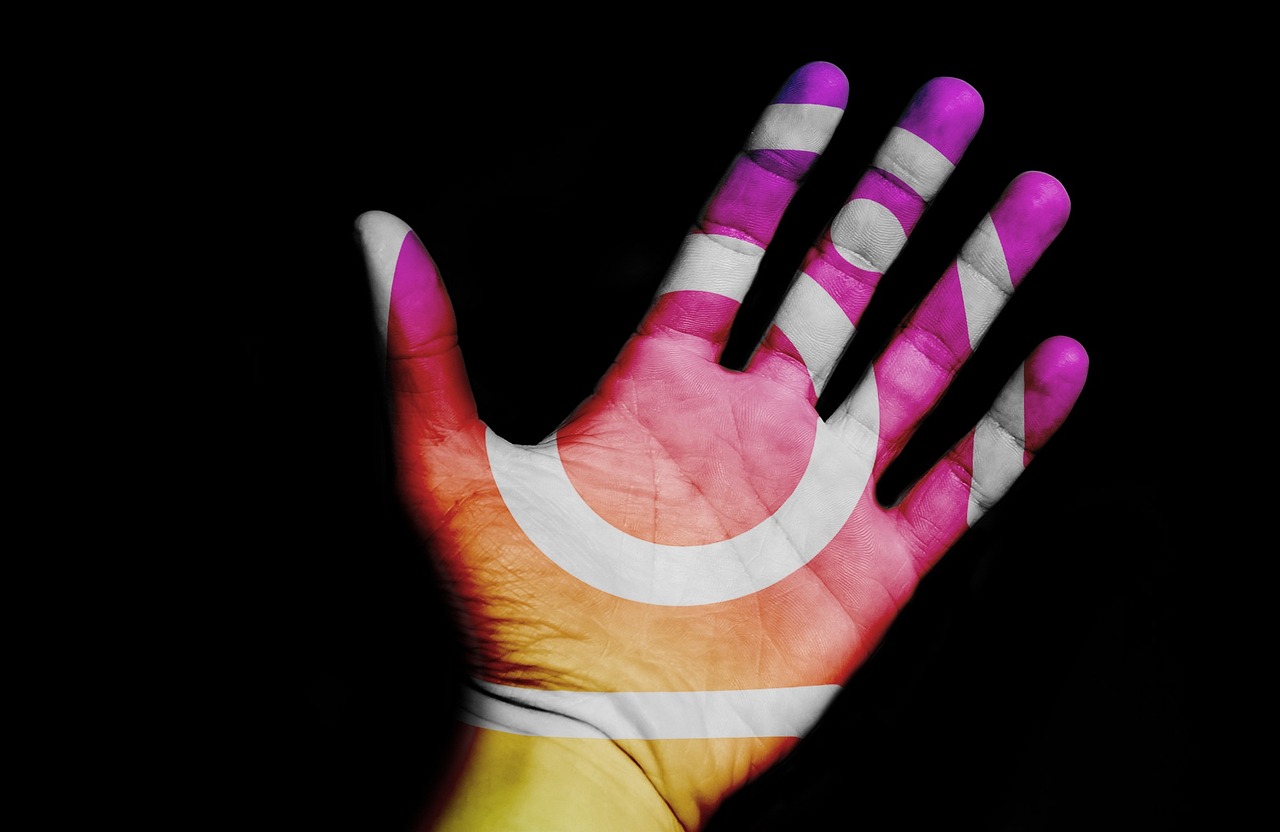 Close-up de uma mão esquerda pintada com o logotipo do Instagram. Os dedos estão levemente flexionados e a palma da mão está voltada para a câmera. O logotipo do Instagram é branco e está localizado no centro da palma da mão.