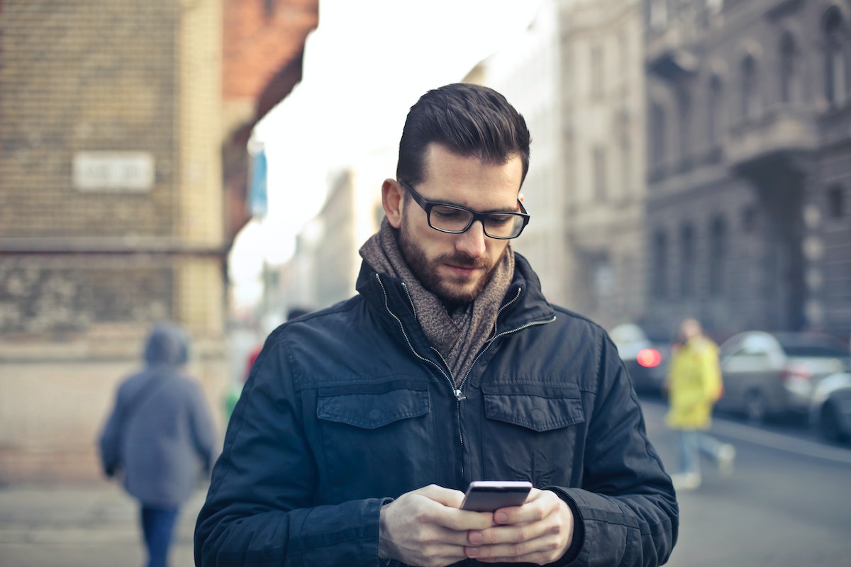 Uma pessoa está andando na rua enquanto mexe em um smartphone de tela dobrável