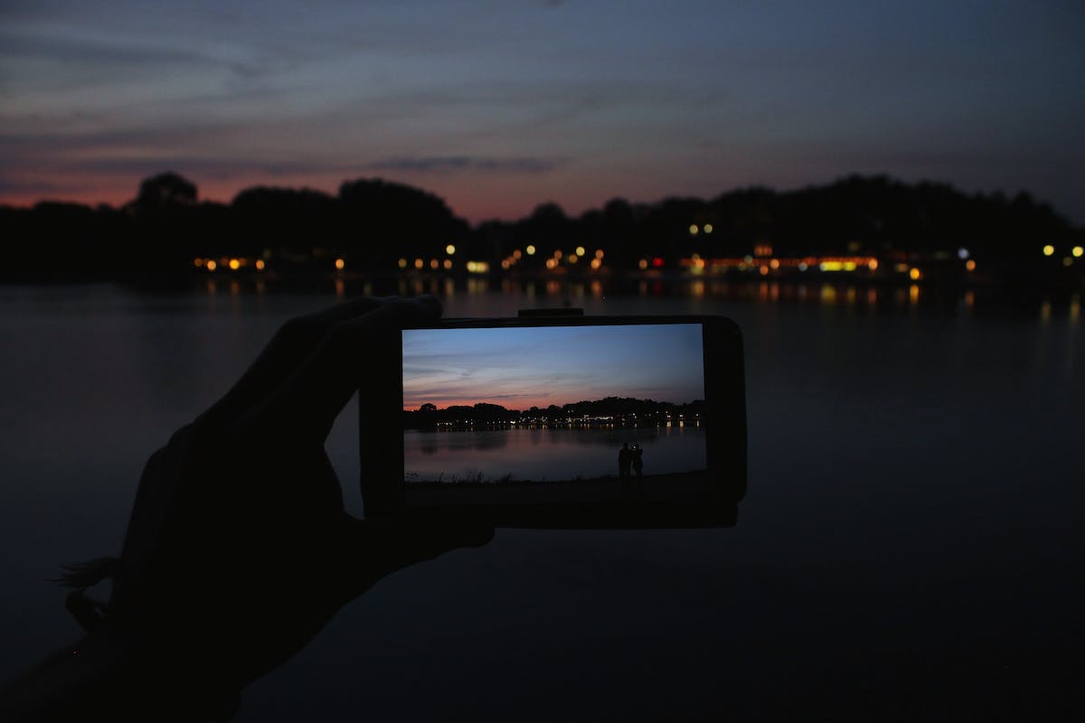 Uma mulher tentando tirar foto da lua em cena com baixa luminosidade com o iPhone 13