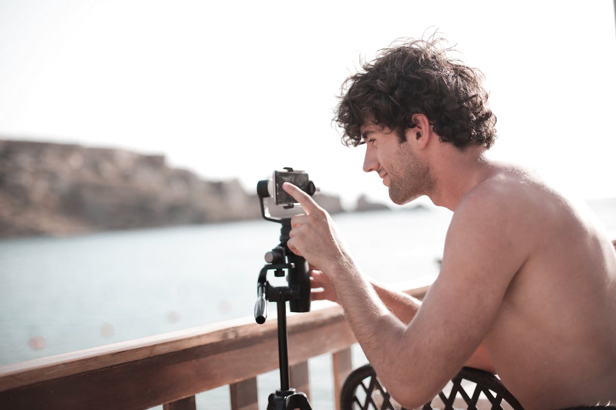 Um home está posicionando seu celular com câmera Motorola alta definição para tirar uma foto do mar