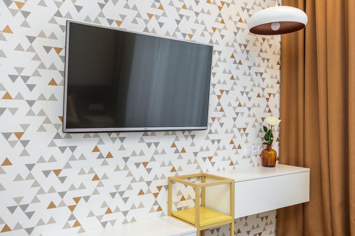 Uma Smart TV está na parede que tem um papel. É possível ver duas gavetas suspensas