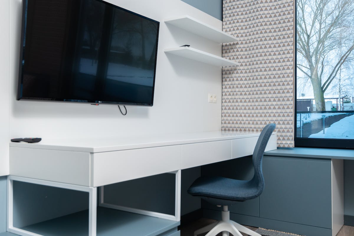 Em um escritório há uma mesa, uma cadeira e uma TV 4k barata 2023 em um painel