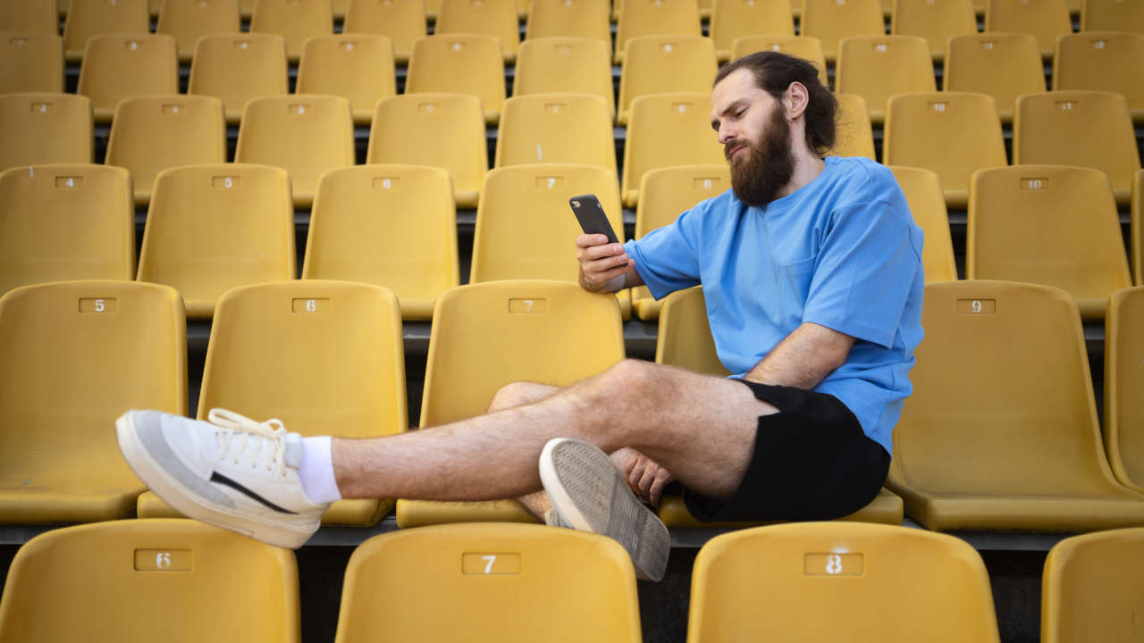 Homem assistindo jogos do Brasil pelo celular em estádio