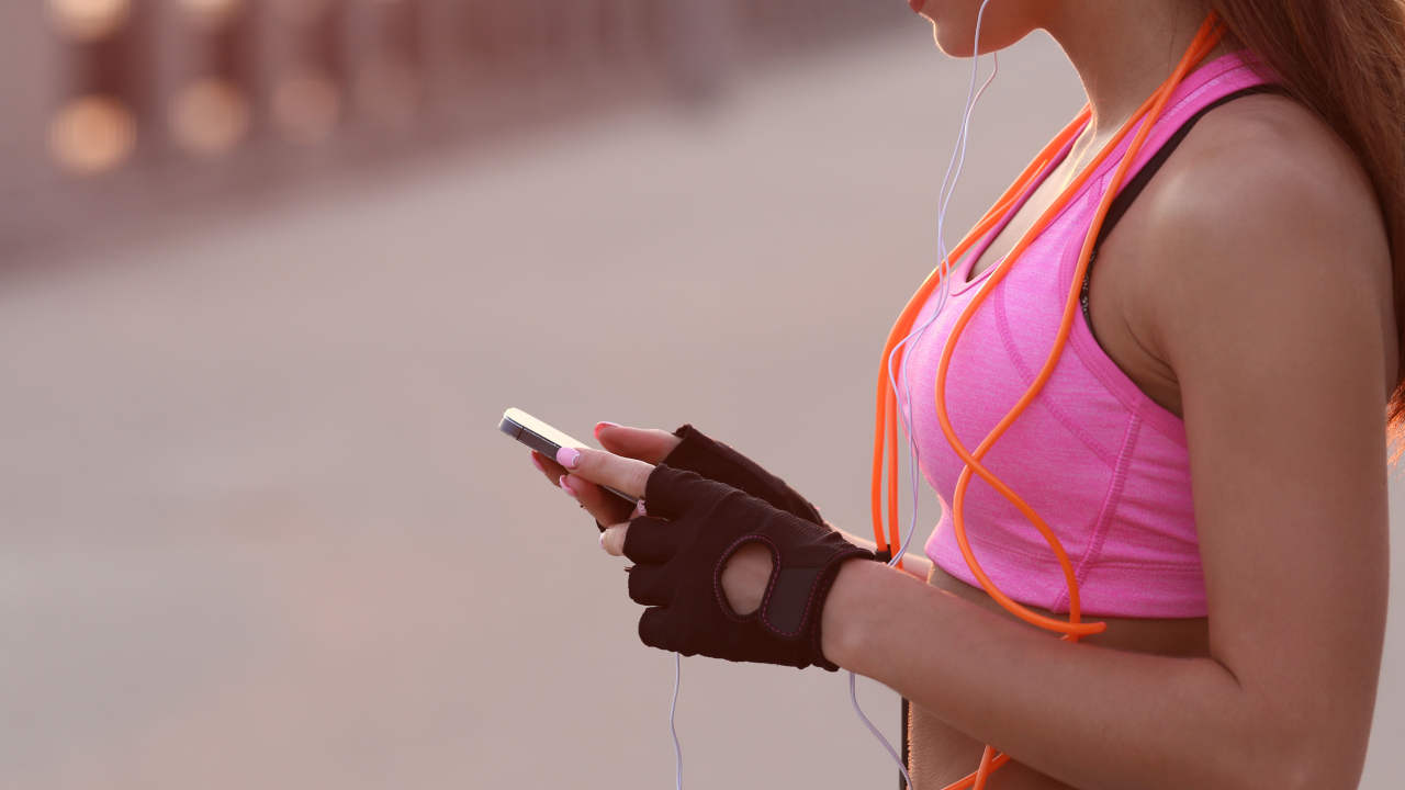 Mulher segurando o celular enquanto usa os melhores aplicativos para caminhada e corrida