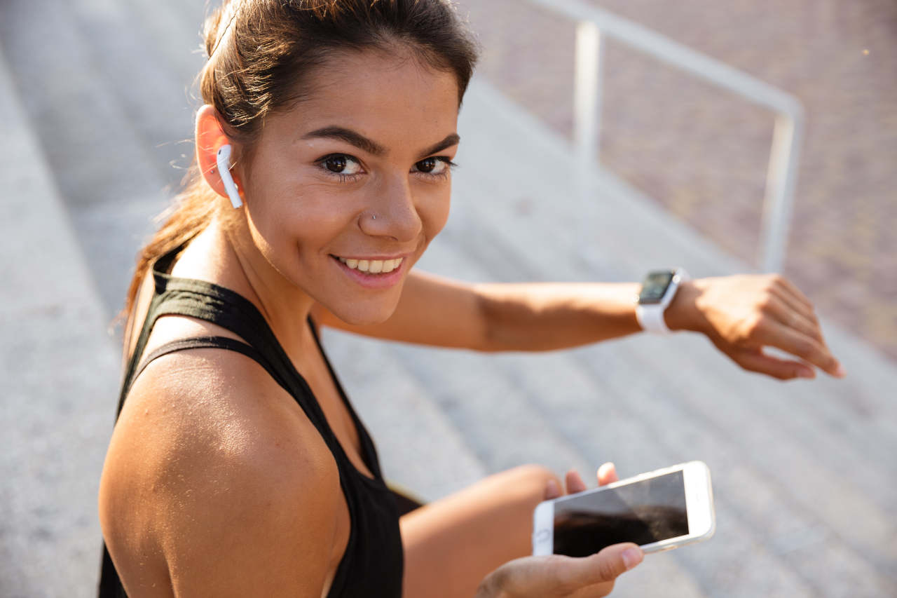 Mulher olhando para câmera e sorrindo enquanto conecta aplicativo com seu smartwatch 