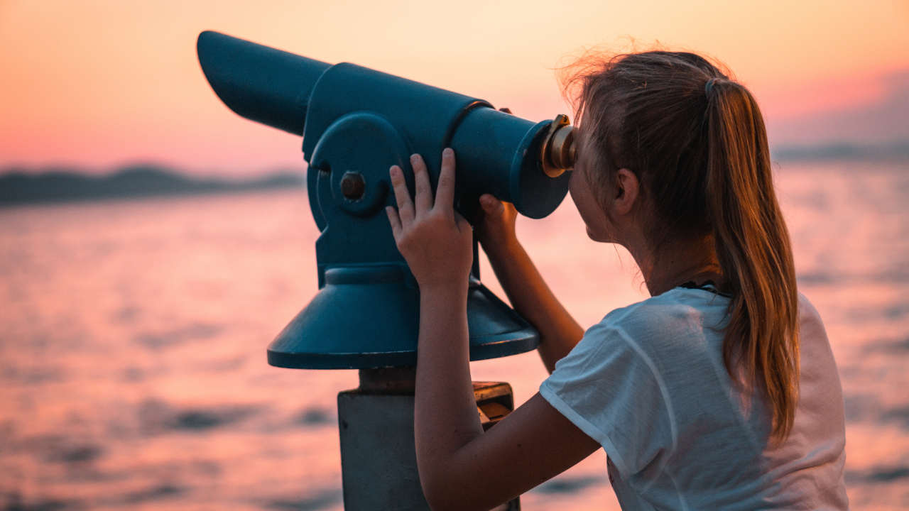 Mulher olhando para o céu usando telescópio