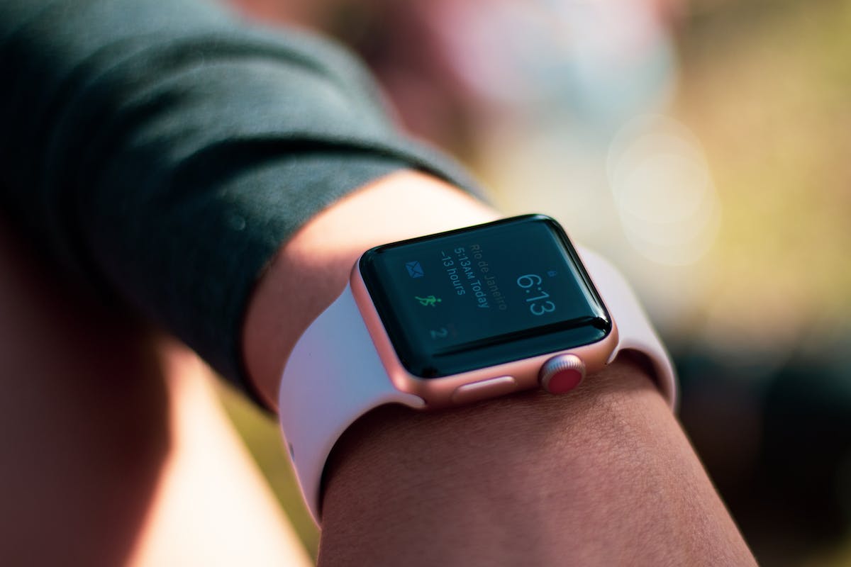 Um smartwatch Apple Watch Series 4 em uma pulseira de silicone preta está mostrando a hora e a data. O texto na tela do relógio diz "6:13 Rio de Janeiro -13 horas 5:13AM Today".