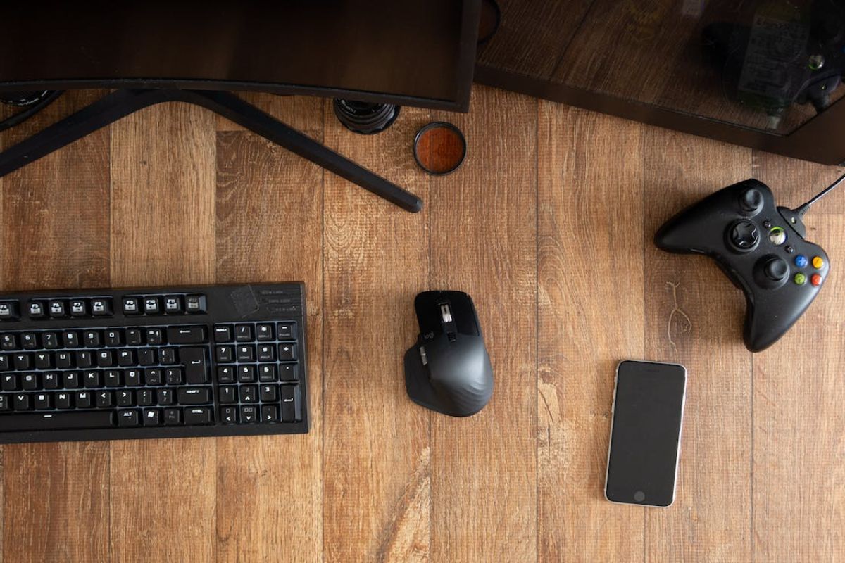 Equipamentos em cima da mesa: há um teclado, celular e mouse