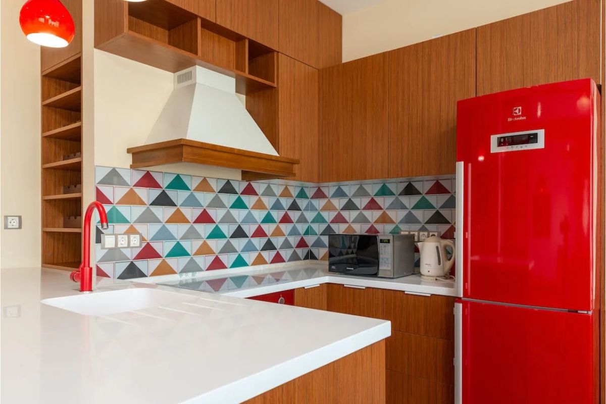 Foto de uma cozinha colorida, marrom com azulejos, e uma geladeira vermelha