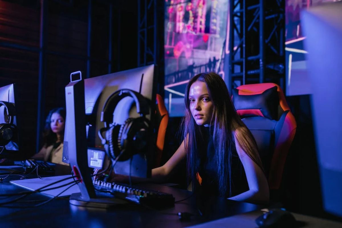 Uma menina está sentada em uma cadeira gamer enquanto mexe em seu Computador Gamer