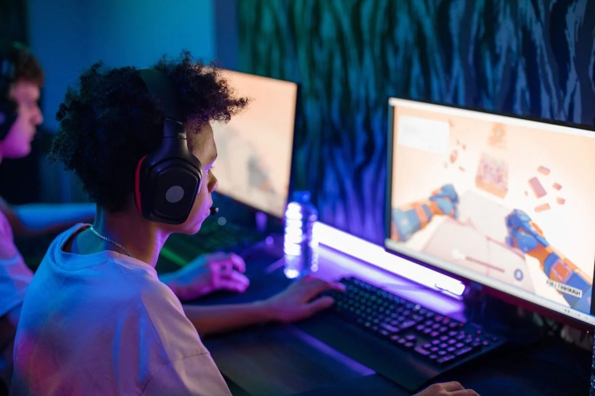 Um gamer está senado na frente de um computador enquanto joga um FPS