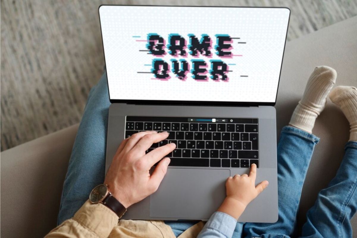 Foto de uma pessoa com um Notebook Gamer 2024 no colo. Na tela aparece escrito "Game Over"