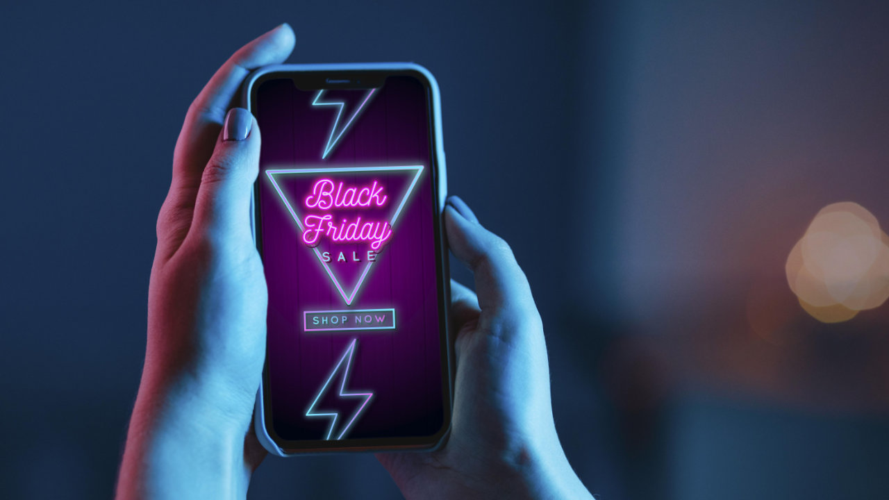 Pessoa segurando celular com imagem de promoções da Black Friday 2023