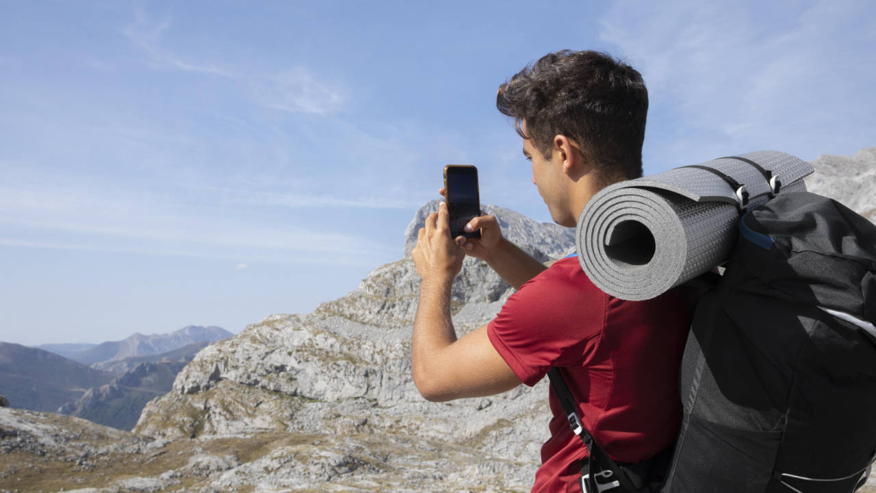 Jovem nas montanhas fazendo trilha tirando foto com celular bom da Blackview