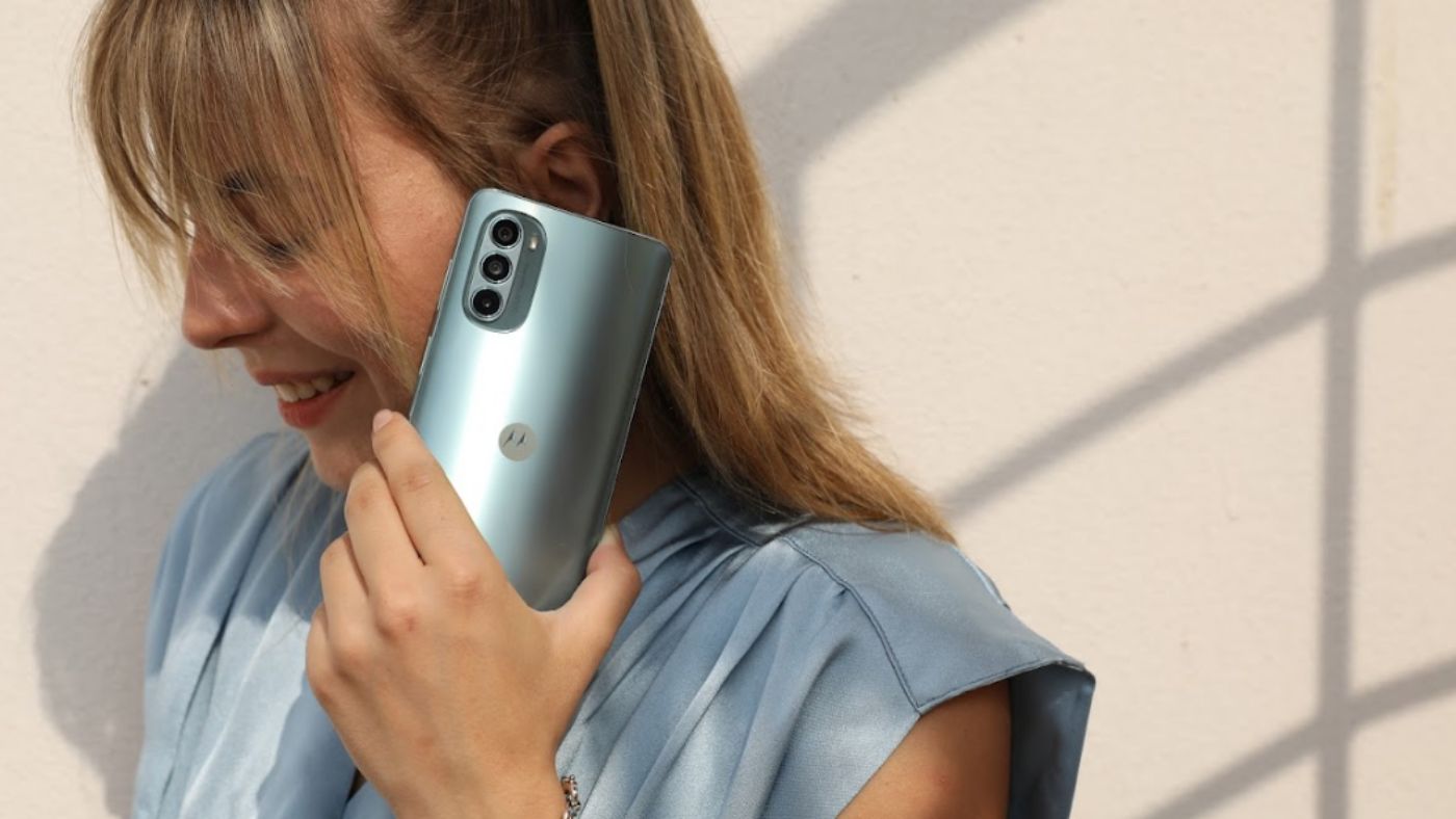 Moça com o celular Moto G62 5G na cor grafite, próximo a orelha