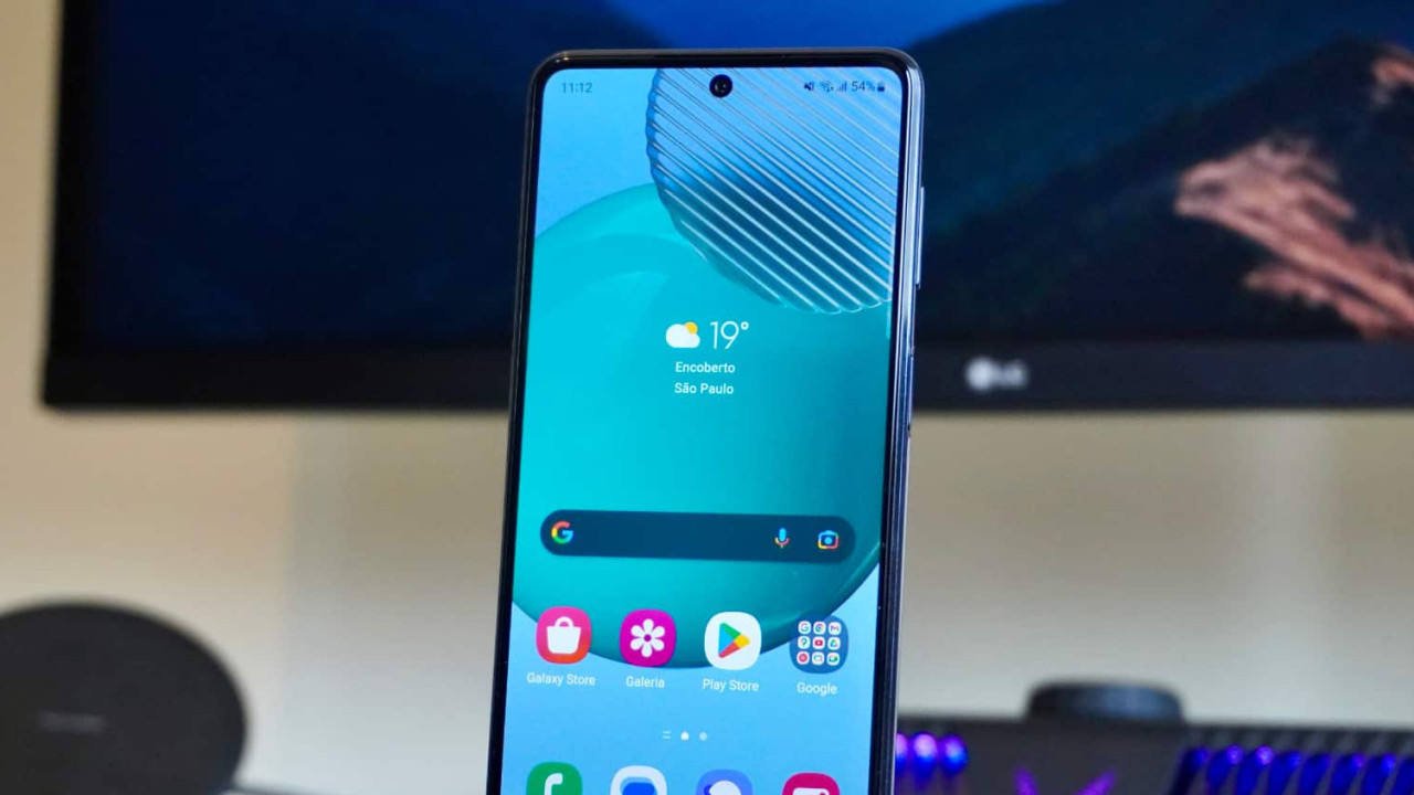 Tela do celular Galaxy M54 5G , com televisor ao fundo