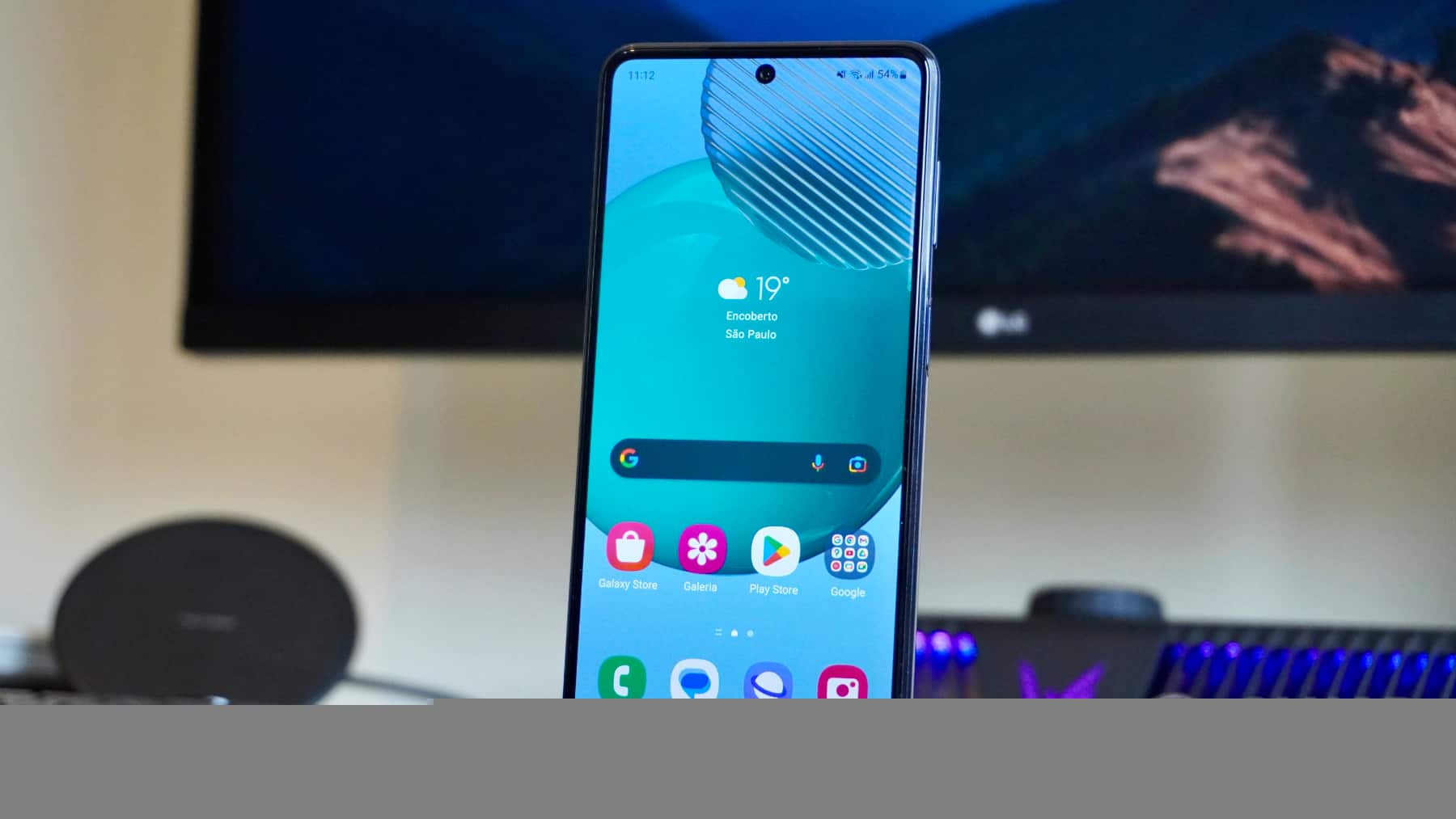 Tela do celular Galaxy M54 5G , com televisor ao fundo