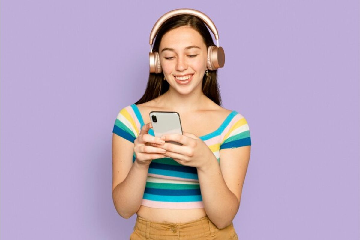 Uma menina com headphone mexe no seu celular enquanto busca sua Retrospectiva Apple Music 2023