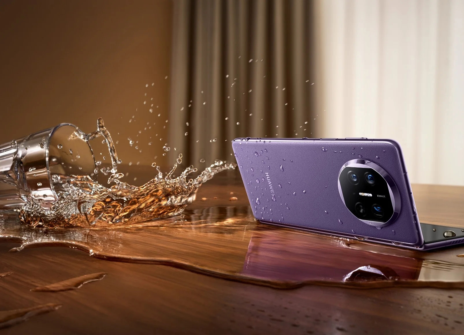 Celular Huawei Mate X5 na cor roxa, apoiado em uma mesa enquanto um copo com água cai ao seu lado