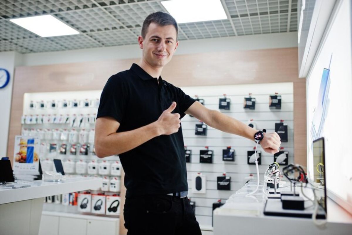 Um homem testa um smartwatch dentro de uma loja e faz sinal de positivo