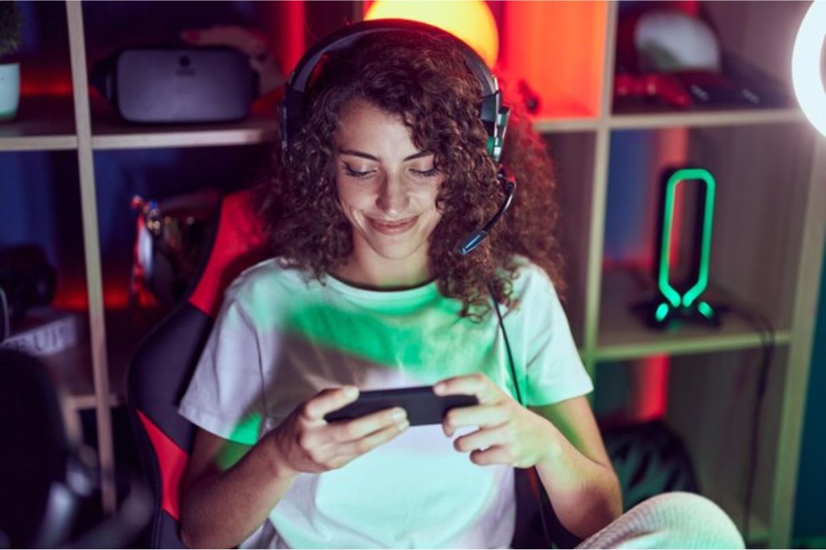 Uma mulher jogando no Lançamento VALORANT Mobile 2024. Ela um headphone e está sentada em uma cadeira gamer