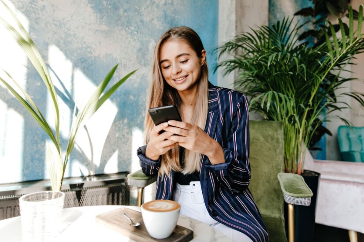 Uma mulher está mexendo no seu smartphone vendo Como Fazer um Currículo pelo Celular