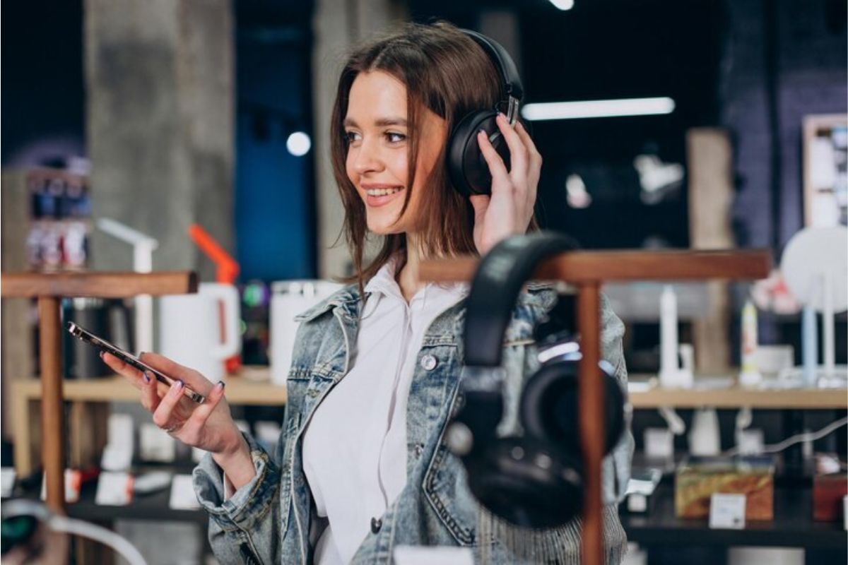 Uma mulher testando um headphone dentro de uma loja de letrônicos