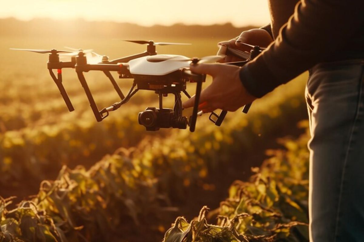Um homem segura um drone enquanto ele está pousando em um campo