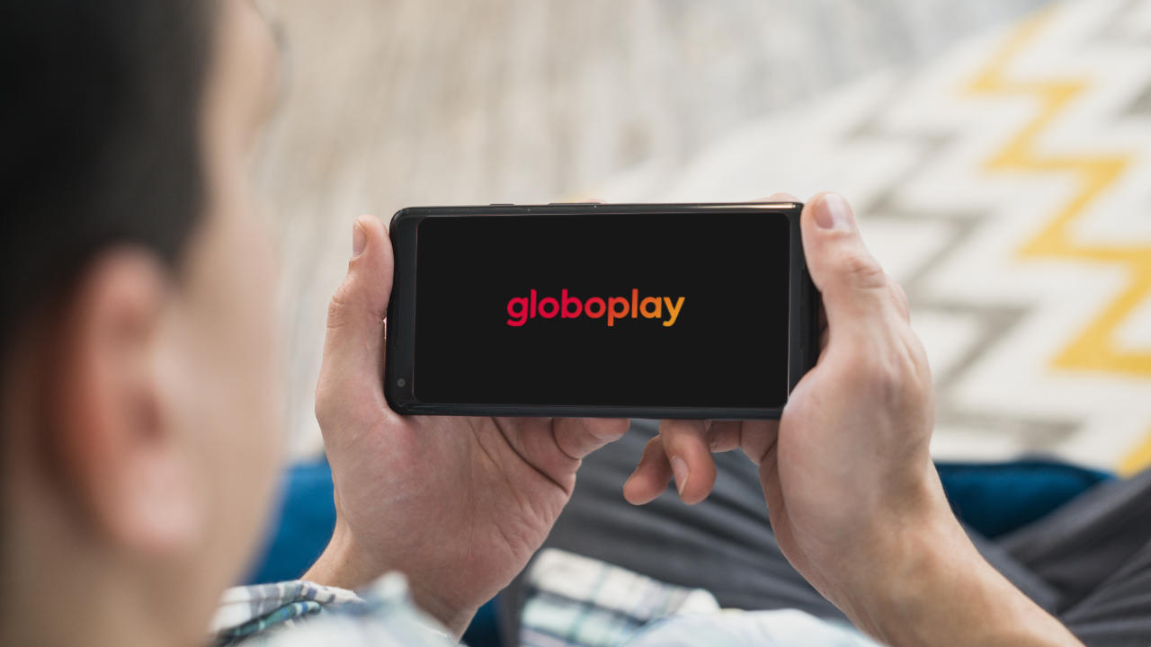 Homem com celular para assistir Globo de graça na Globoplay