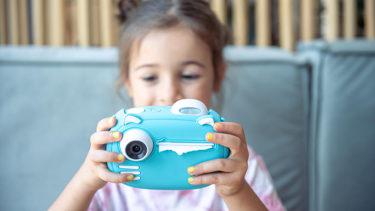 Menina mexendo em uma câmera fotográfica infantil